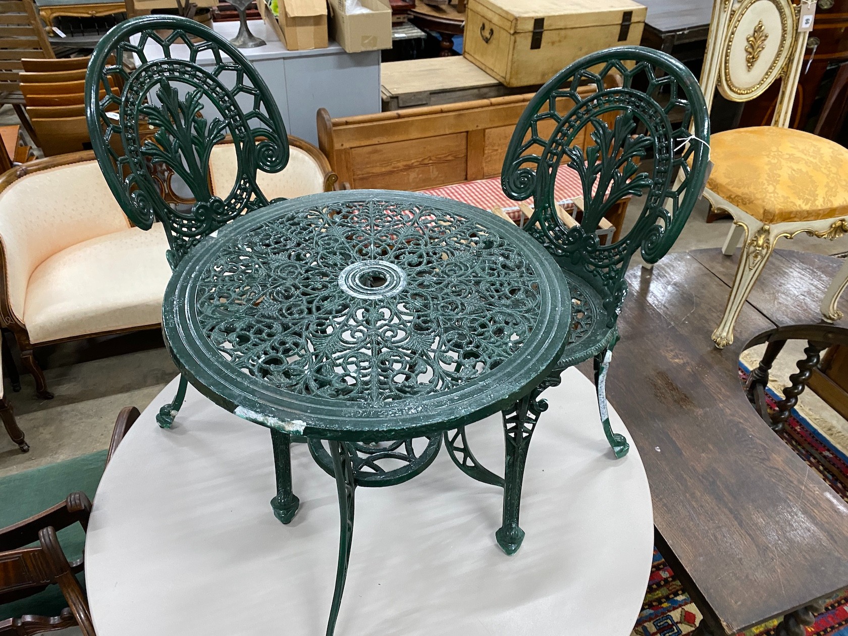 A Victorian style aluminium garden table, diameter 60cm, height 62cm and two chairs